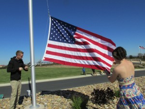 Gunners Mate 3/c David Hess and Aviation Ordinanceman Elizabeth Flemming, both of the USS Essex (LPH 2), hoist a brand new flag into place on the Avenue of Flags at Miramar National Cemetery.